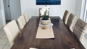 A dining room with a long wooden table, beige chairs, and a woven basket centerpiece.