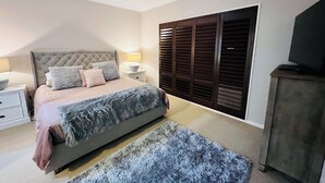 A bedroom with a bed, nightstands, a TV, and a wardrobe.