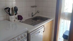 A kitchen with white tiles, a stainless steel sink, wooden cabinets, and a stove. - 2-room South/West with Wifi in Tignes, 5 sleeps, mountain view (Tignes)