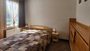 A bedroom with a wooden bed, a small bedside table, a nightstand, and a wooden dresser. - 2-room South/West with Wifi in Tignes, 5 sleeps, mountain view (Tignes)