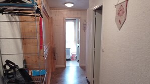 A narrow hallway with a metal rack on the left, a door at the end, and a wall-mounted sign on the right. - 2-room South/West with Wifi in Tignes, 5 sleeps, mountain view (Tignes)