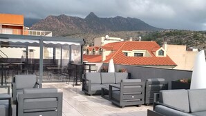 Une terrasse sur le toit avec des sièges en plein air, une structure vitrée et une vue imprenable sur les montagnes.