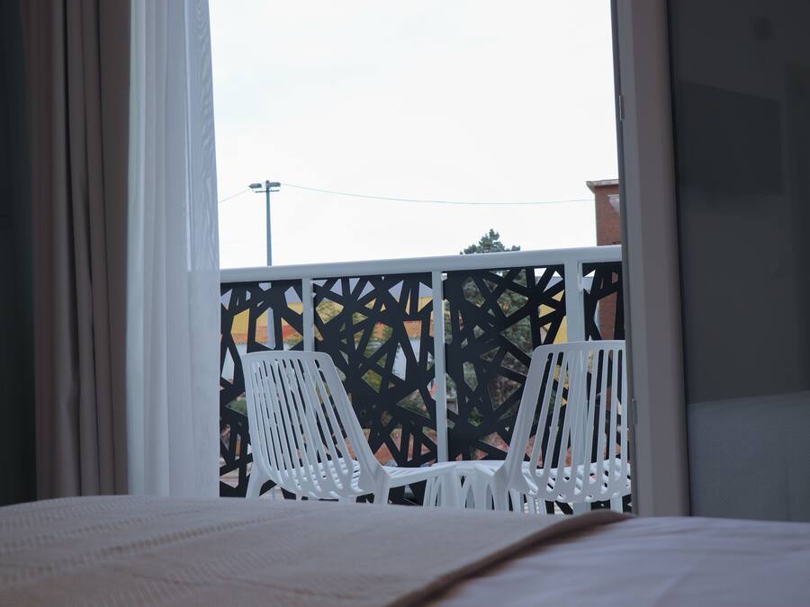 Un balcón con sillas blancas y vistas al exterior.