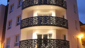 Un hôtel à plusieurs étages au design moderne, doté de balcons ornés de motifs complexes en treillis et d’une enseigne « Suvna » au niveau du rez-de-chaussée.