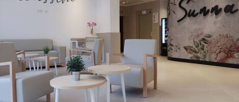 A modern lobby with seating areas, a reception desk, and a floral wall.