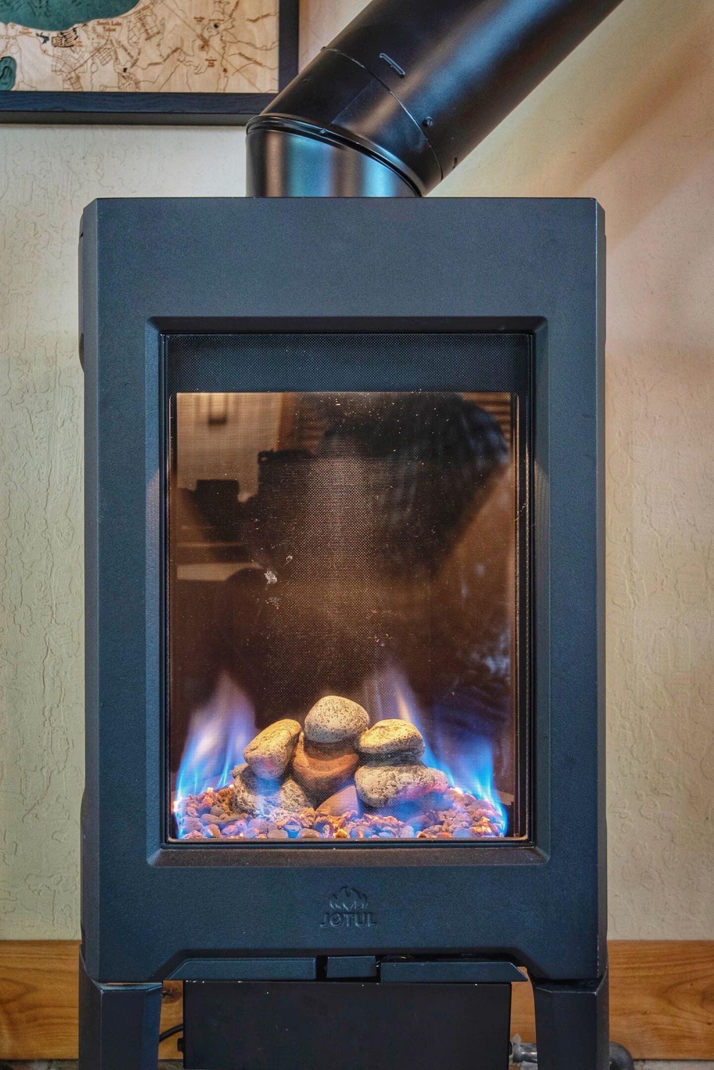 A black wood-burning stove with a glass front, displaying a fire burning inside.