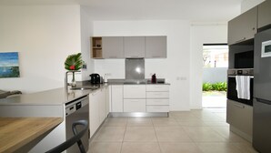 Cozinha moderna com armários brancos, máquina de lavar louça embutida e exaustor de aço inoxidável.