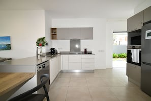 A modern kitchen with white cabinetry, a built-in dishwasher, and a stainless steel range hood. - Modern White and Blue on the beach with pool (Poste Lafayette)
