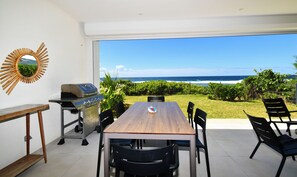 A dining area with a view of the ocean, a grill, and a decorative mirror.