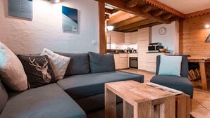 Un soggiorno moderno con un divano componibile, un tavolino in legno e una cucina sullo sfondo.