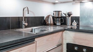 Una cucina moderna con lavello in acciaio inossidabile, una macchina da caffè e un bollitore.