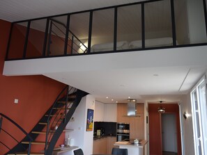 Experience the sleek, multi-level apartment with a compact kitchen, dining space, and spacious living area.