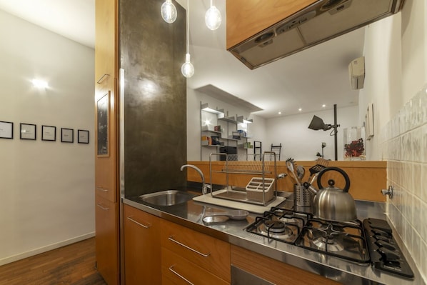 A modern kitchen with a stainless steel sink, wooden cabinets, and a gas stove.