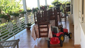 A covered outdoor area with a patio table, a red and green plastic play structure, and a red toy tractor. - Villa des Cymbidiums (Le Tampon)