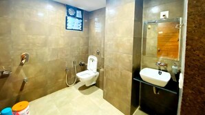 A modern bathroom with a toilet, shower, and sink. - Hotel Prime (Gandhinagar)