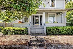A two-story house with a porch, steps leading to the front door, and a mailbox.