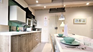 A modern kitchen with wooden cabinets, a white countertop, and a dining area with a table set for two. - Wine Apartments Florence Grechetto (Florence)