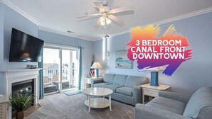 Eine 3-Zimmer-Wohnung am Kanal in der Innenstadt mit Wohnzimmer, Kamin, Fernseher und Deckenventilator.