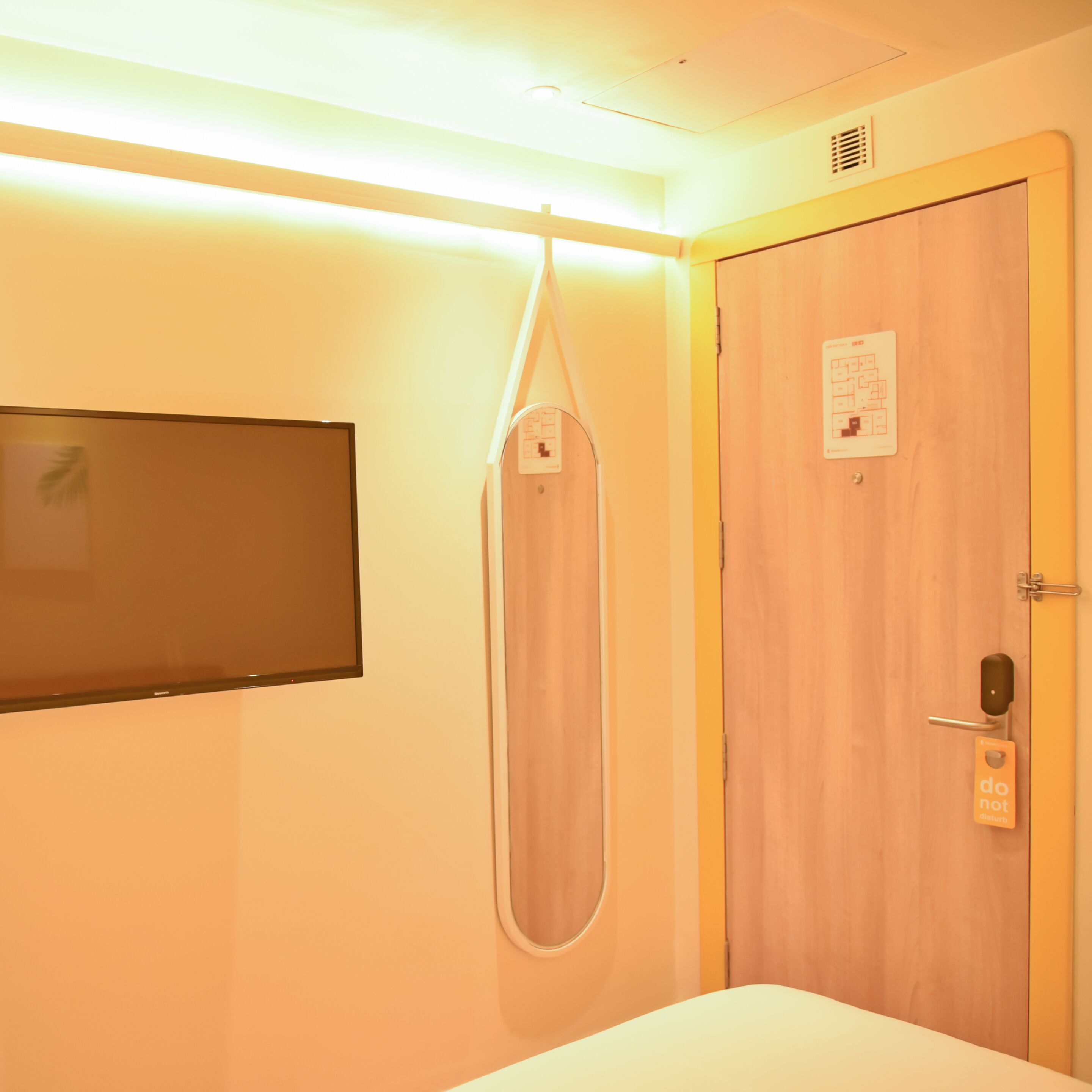 Habitación de hotel con cama, sillón de masaje colgante, televisor montado en la pared y puerta con cartel de ‘No molestar'.