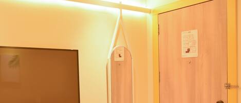 Habitación de hotel con cama, sillón de masaje colgante, televisor montado en la pared y puerta con cartel de ‘No molestar'.