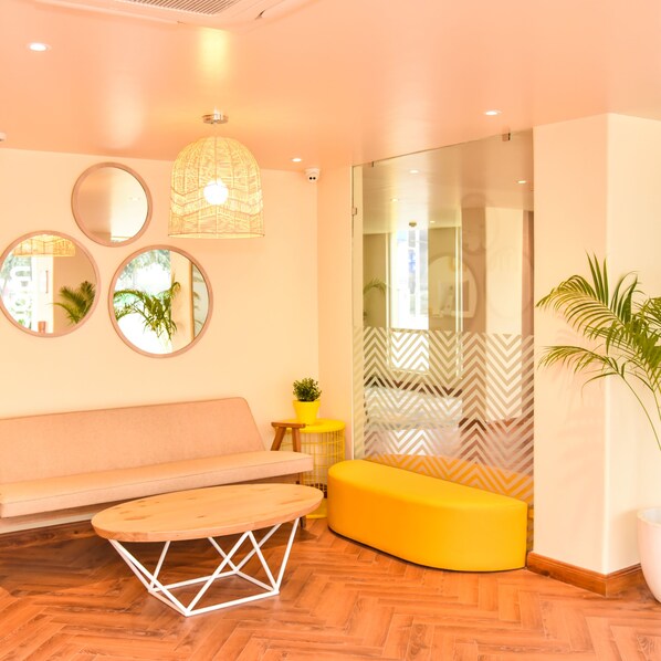 A modern interior with a wooden floor, a sofa, a yellow ottoman, and a round table.