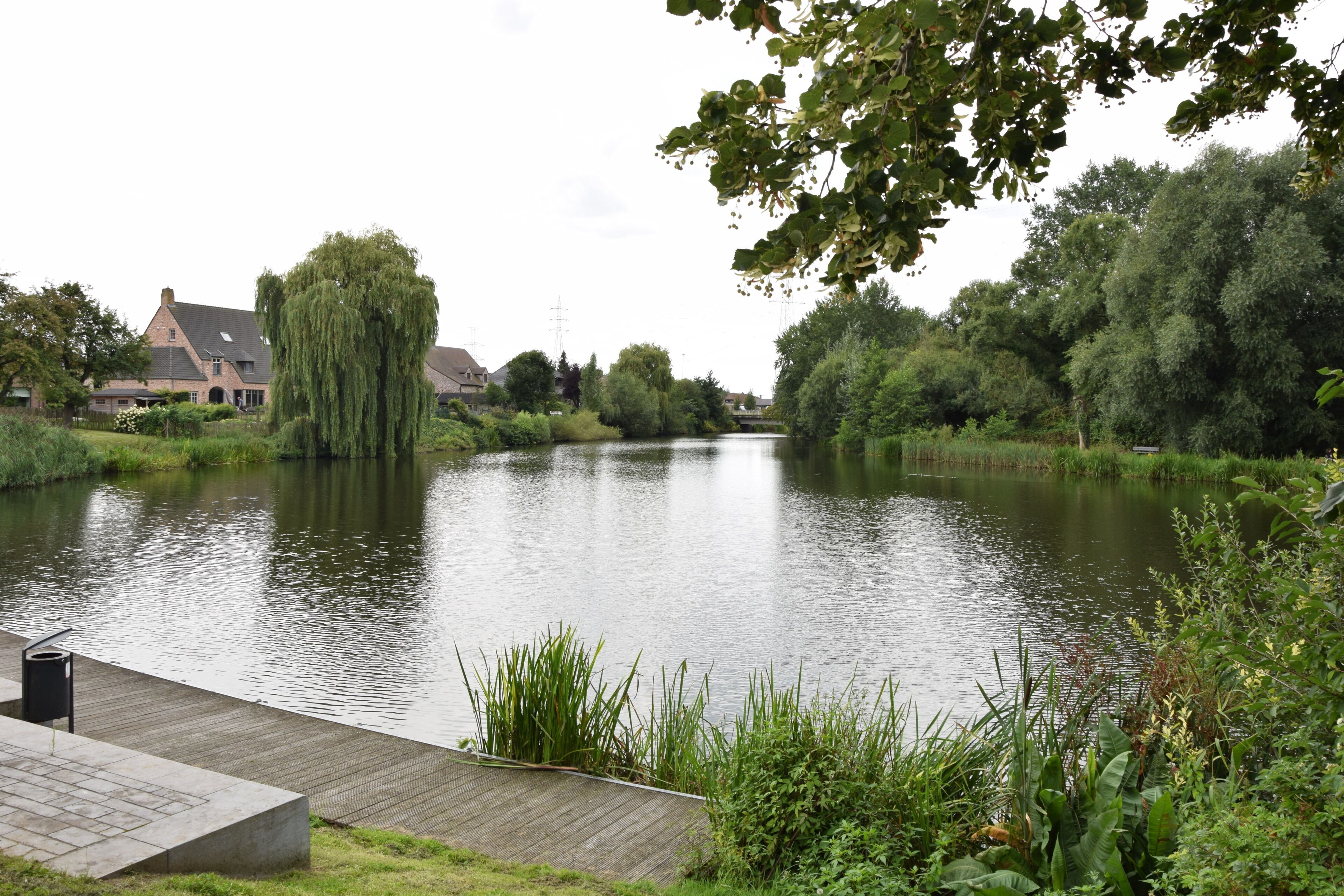 Blick auf einen Fluss mit einer hölzernen Anlegestelle, einem Haus und üppigem Grün.