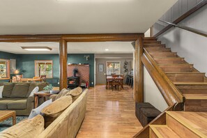 Un vaste espace de vie comprenant une cheminée, une table à manger et un escalier.