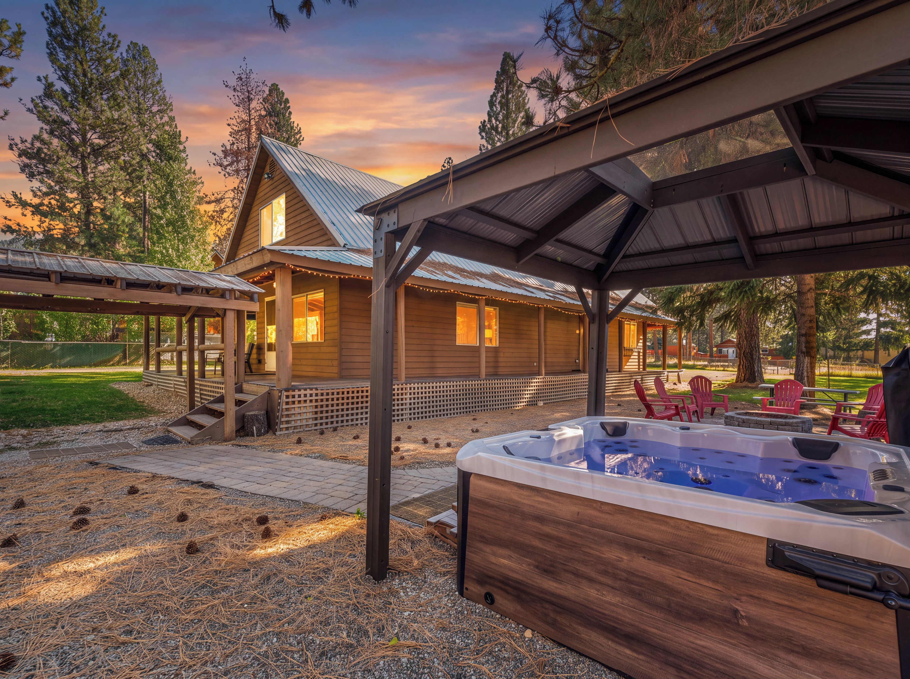 A wooden cabin with a covered patio area, a hot tub, and outdoor seating.
