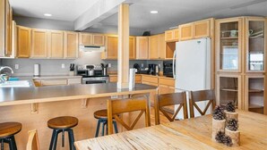 Una cocina moderna con armarios de madera, una isla central y taburetes de bar.