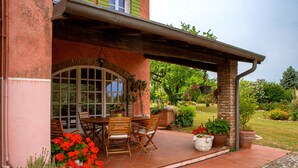 A patio with a table and chairs, surrounded by potted plants and a brick wall.