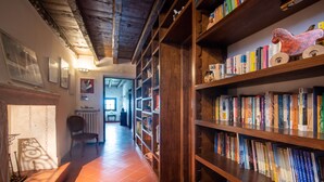 A hallway with wooden bookshelves filled with books, a chair, and a radiator.