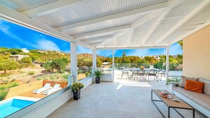 A covered outdoor area with a pool, lounge chairs, a dining table, and a sofa. - Etoile Villa Heated Pool (Agios Nikolaos)