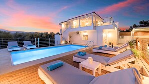 A modern villa with a swimming pool, outdoor seating, and a scenic sunset view. - Etoile Villa Heated Pool (Agios Nikolaos)