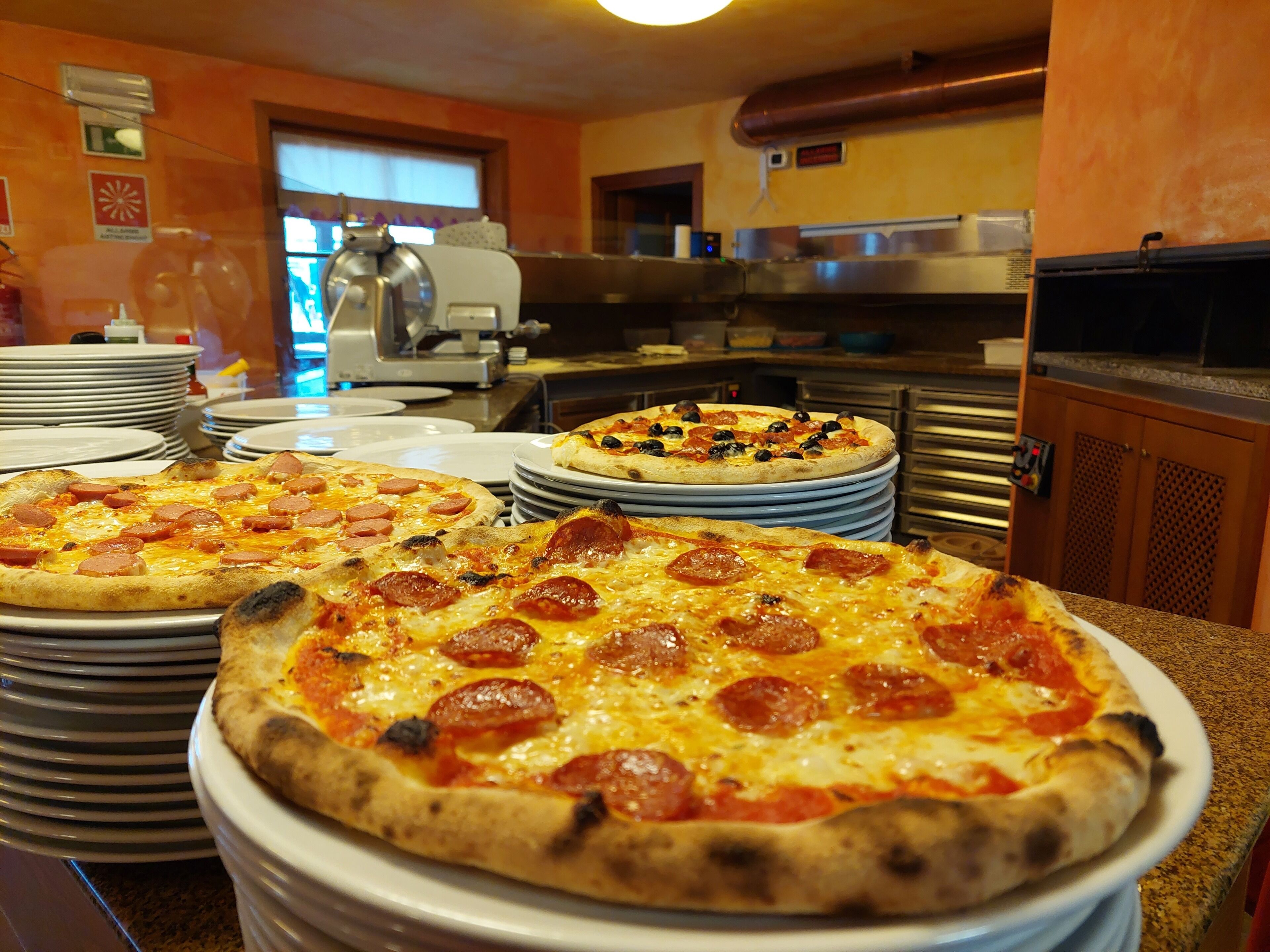 Eine Küche mit mehreren Pizzen auf Tellern, einer Kaffeemaschine und Küchenschränken.
