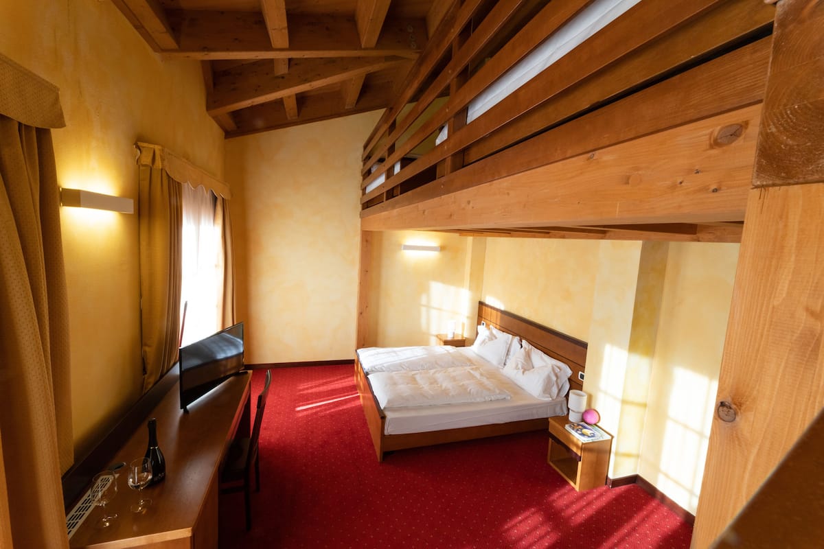 Ein Zimmer mit Holzboden, einem Bett, einem Schreibtisch und einem Fenster.