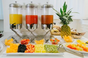 A breakfast buffet with fruit, juice dispensers, and a pineapple. - Hotel Enzo Moro (Sutrio)