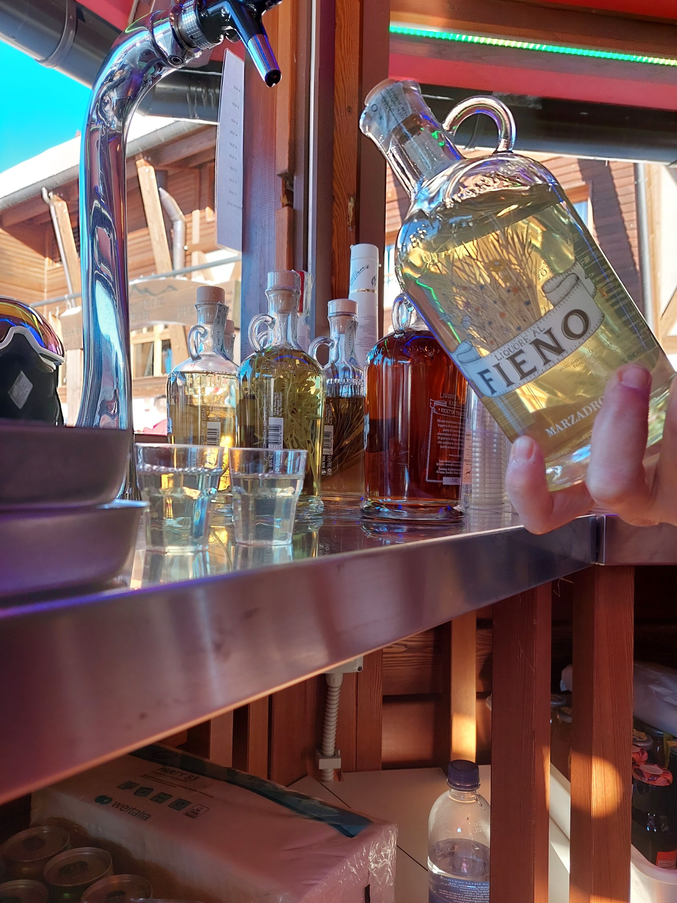 A bar area with a variety of liquor bottles and glasses on a counter.