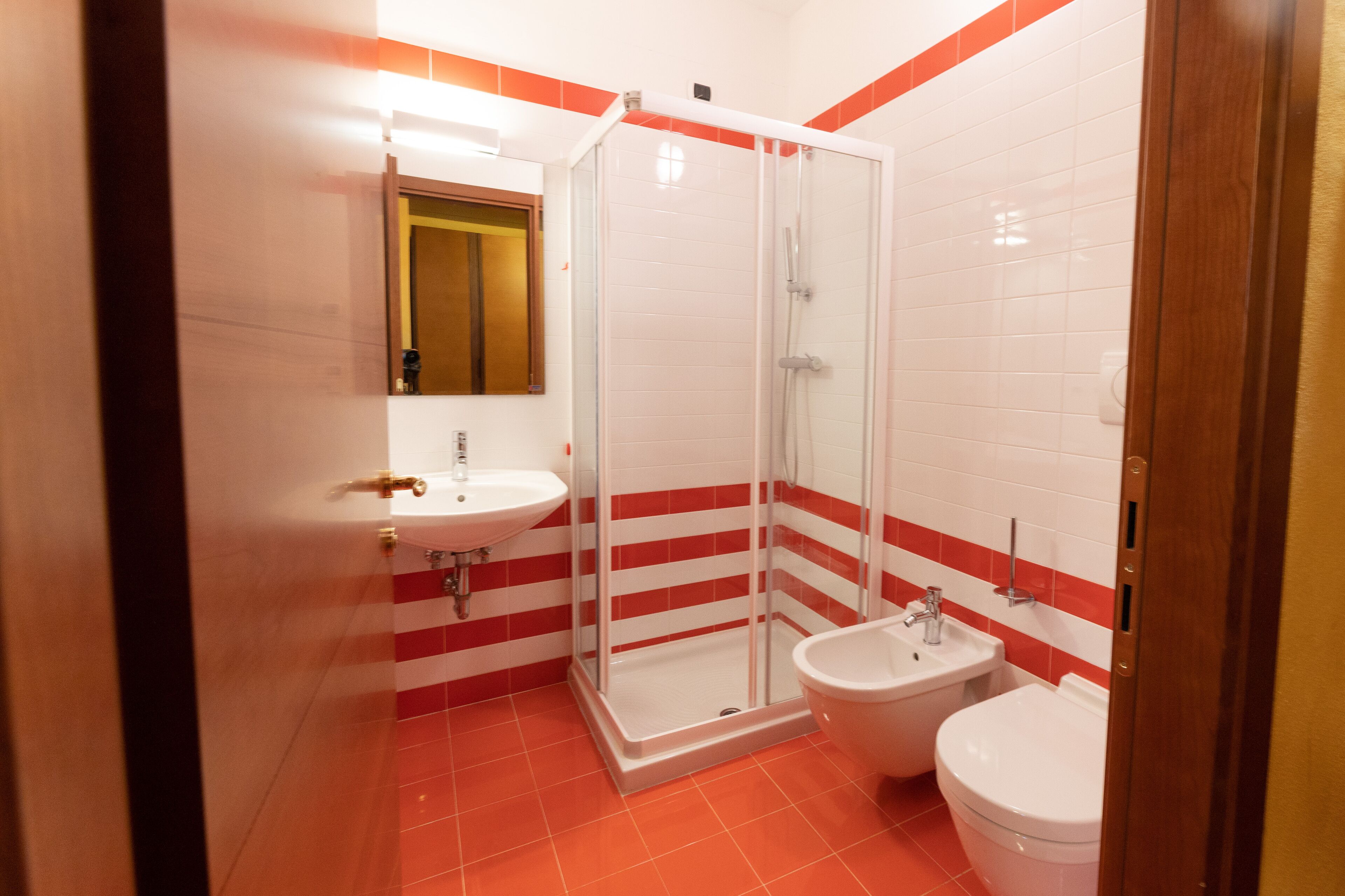 Un baño con ducha envuelta en vidrio, un lavamanos y un inodoro.