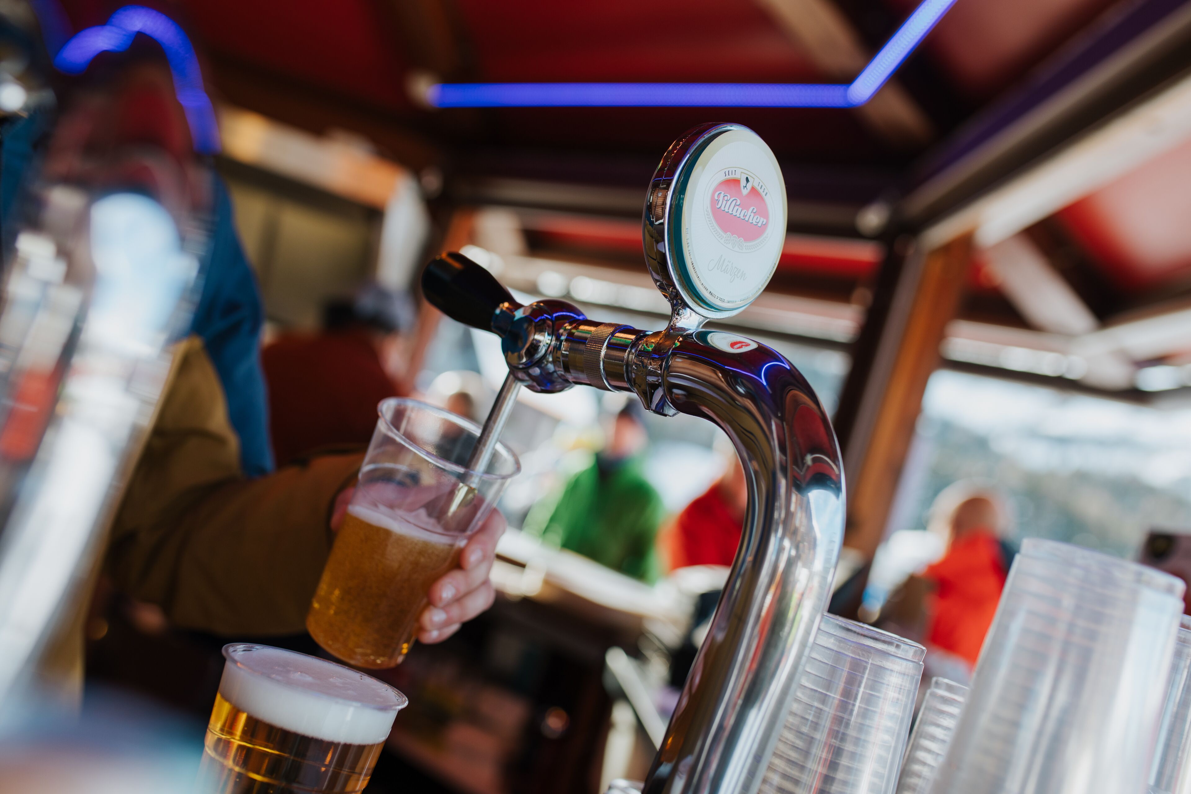 Ein Zapfhahn für Bier, in den gerade ein Glas Bier eingegossen wird.