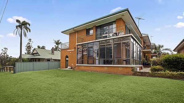 A two-story house with a large glass front and a balcony.