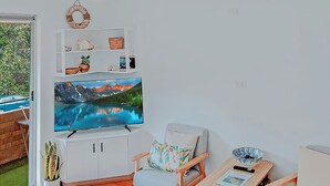 Olohuoneessa on suuri, seinälle asennettu taulutelevisio, sen alla valkoinen kaappi, värikkäällä tyynyllä varustettu puinen tuoli sekä pieni pöytä, jonka päällä on kulho ja kaukosäädin.