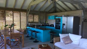 A cozy kitchen with a bar area, wooden furniture, and a white sofa. - Villa Zuli (Deshaies)