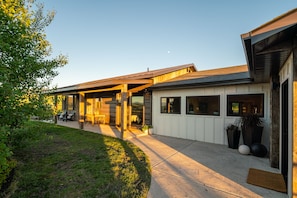 Een modern huis met een overdekt terras, grote ramen en een verzorgd gazon.