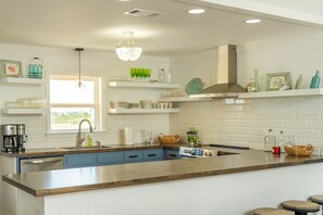Een moderne keuken met een houten aanrecht, een ingebouwde vaatwasser en een raam dat voor natuurlijk licht zorgt.