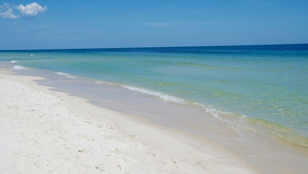 A beach with clear turquoise water and white sand.