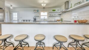 A kitchen with a central island, bar stools, white cabinetry, and a pendant light.