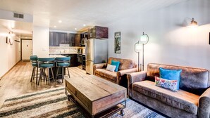 Eine moderne Küche mit dunklen Schränken, einem Kühlschrank und einer Essecke mit Barhocker.