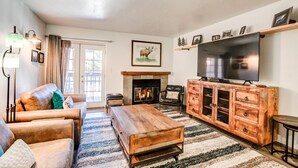 Ein Wohnzimmer mit Kamin, Sofa, Couchtisch, Fernseher und Holzschrank.