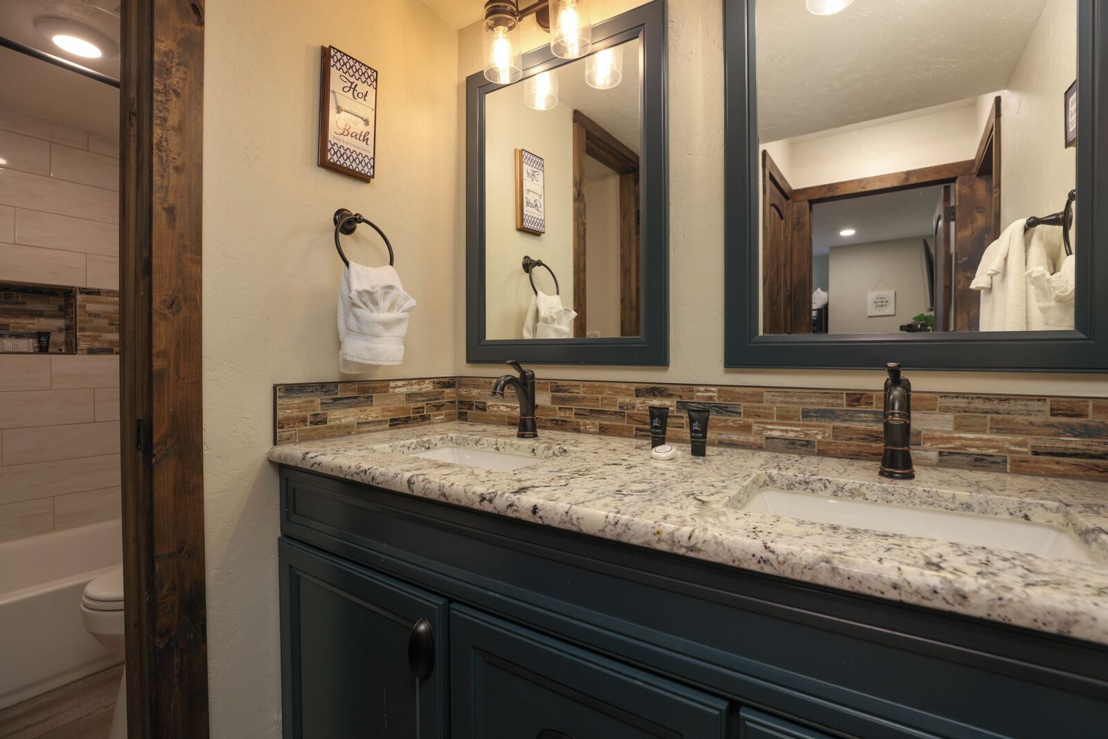A bathroom with a double sink, dark cabinetry, a large mirror, and a towel rack.