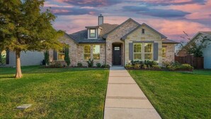 A two-story stone house with a front entrance, a covered porch, and a well-maintained lawn. - Trendy and Modern home w/ a Private Pool (Rowlett)